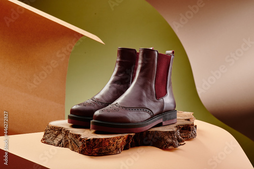 Burgundy leather chelsea boots made of genuine leather in classic style on a wooden cut. Close-up. High quality photo