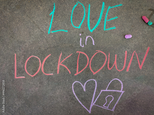 The inscription text on the grey board, Love in lockdown with hand drawn love symbol and lock. Using color chalk pieces.