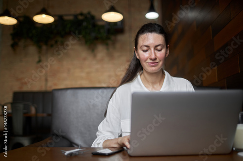 Business woman with laptop. She is working and relaxing at a cafe drinking latte
