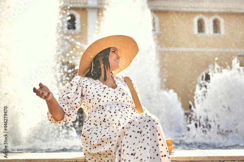 mujer en el centro de sincelejo con  sombrero sonriendo mirando hacia un lado y fuente de agua  en la parte de atras photo