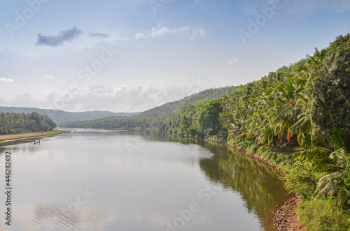 Picturesque view of Phalguni River with hills and fields in the background at Polali, Mangalore, Karnataka, India © DSLucas