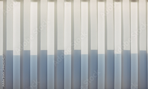 Abstract geometric vertical lines white and gray gradient color. Repeating pattern  background texture  design of striped lines. Blinds illuminated by the sun  close-up.
