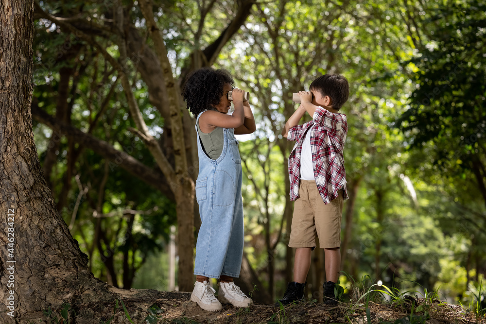 American little girl and boy explorer with his paper binoculars in the nature American little girl and boy explorer with his paper binoculars in the nature