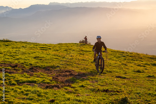 Girl child riding mountain bike into the sunset. Beautiful golden summer light.