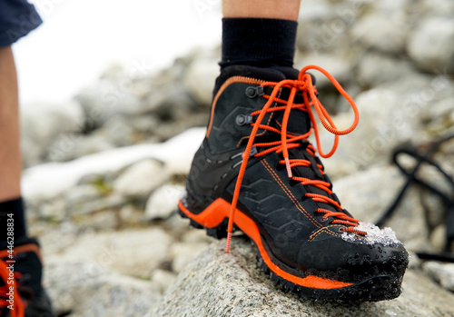 Close up of mountain shoes in black and orange colors with show on the nose