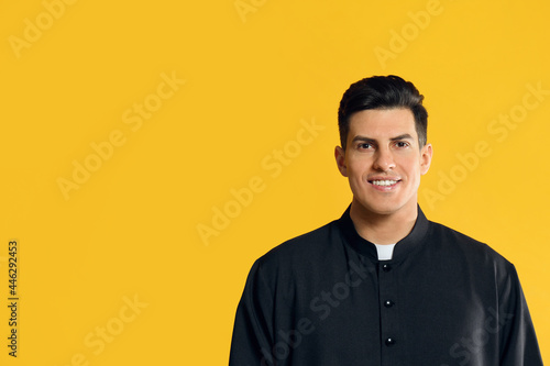 Priest wearing cassock with clerical collar on yellow background. Space for text