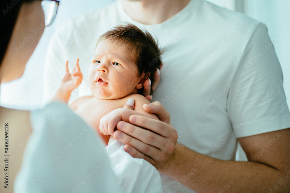 Obraz premium Unrecognizable parents with newborn baby girl. Close up portrait of two week old sweet new born baby attentively looking on her mother.