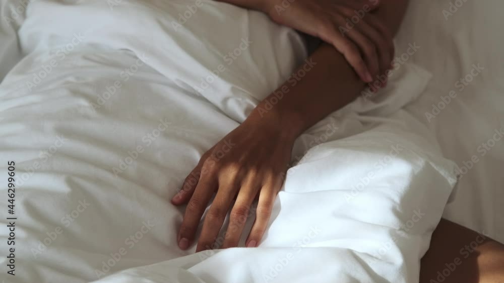 female hands on bed linen during morning wake up, details shot, sleeping at early morning female hands on bed linen during morning wake up, details shot, sleeping at early morning