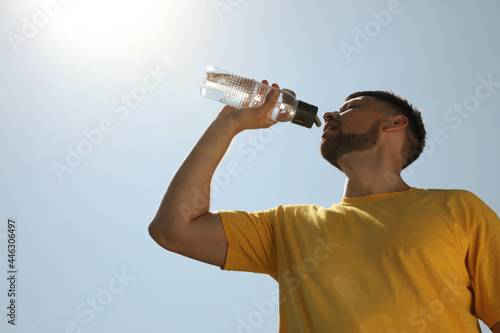 Man drinking water to prevent heat stroke outdoors, low angle view