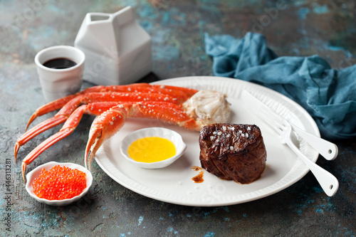 Carnivore-Ketogenic diet lunch or dinner. Filet mignon steak, butter sauce, crab legs and red caviar, selective focus.