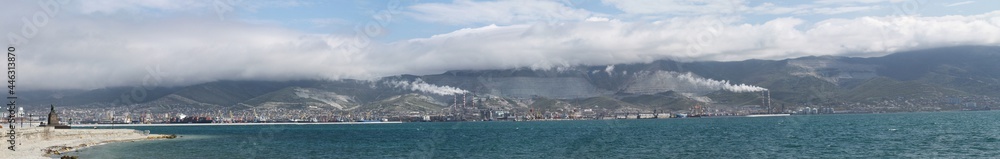 Panorama of the sea bay against the background of factories, ships, mountains and clouds