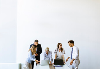 Group of business people with young adults and senior woman colleague on meeting at modern bright office interior