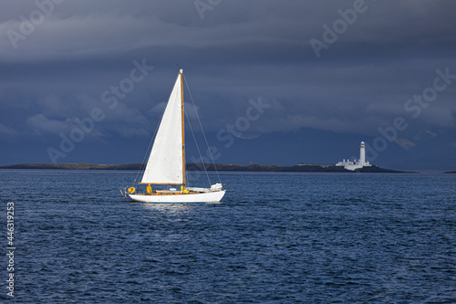 A yacht sailing towards the Eilean Musdile lighthouse on Lismore in the Inner Hebrides, Argyll and Bute, Scotland, UK photo