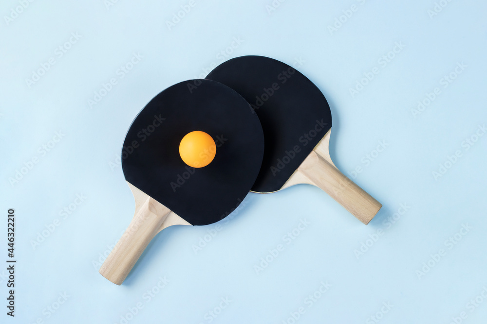 Two black ping pong paddles and one yellow ball Two black ping pong paddles and one yellow ball