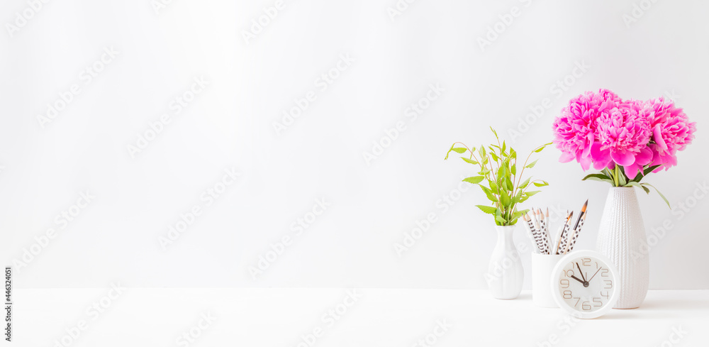 Home office desktop with pink peonies in a vase on a light background Home office desktop with pink peonies in a vase on a light background