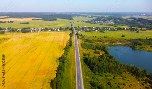 Aerial view of the road through yellow crop fields and meadows © Payllik