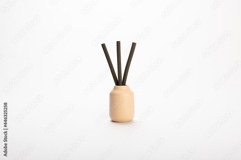 a cream colored ceramicdiffuser jar with brown scented reeds on white background a cream colored ceramicdiffuser jar with brown scented reeds on white background