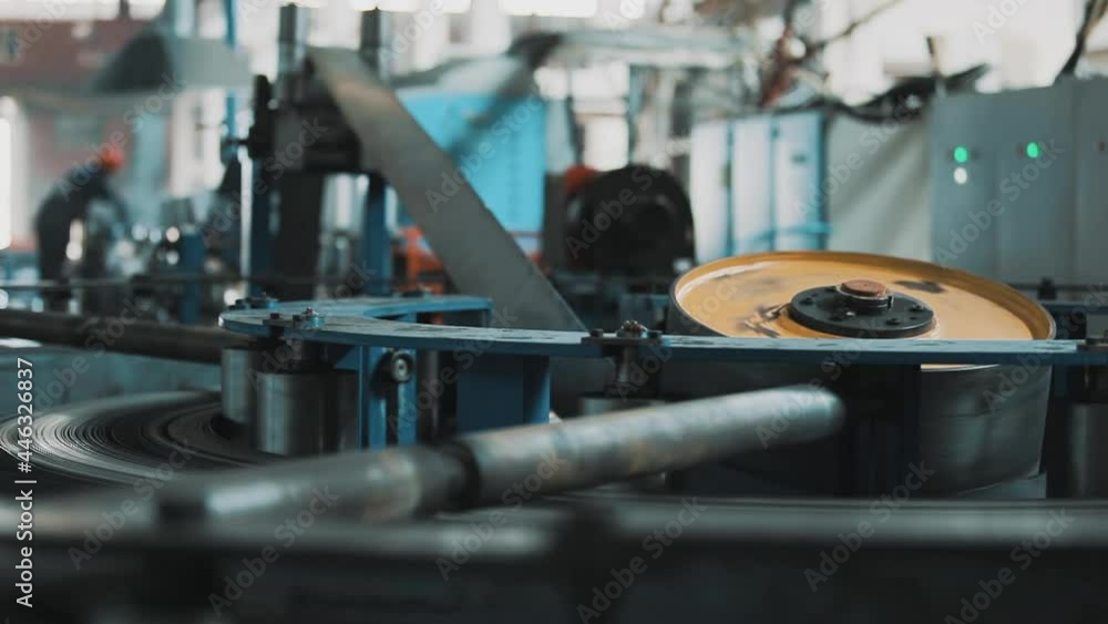 Steel pipe production plant. Special machine in the factory for unwinding steel strips. The round, large bobbin is constantly rotating and the sheets of steel pass through it. Steel pipe production plant. Special machine in the factory for unwinding steel strips. The round, large bobbin is constantly rotating and the sheets of steel pass through it.
