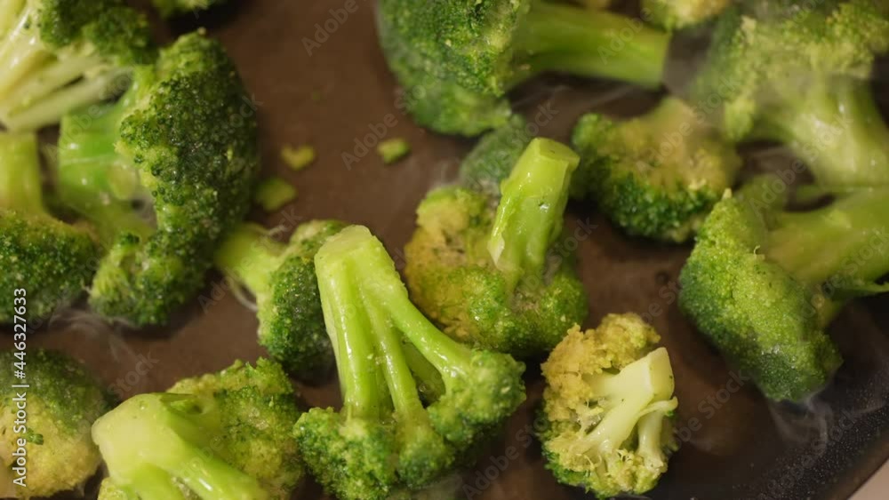 Skillet full of freshly cut broccoli cooking on the stove top - slow motion Skillet full of freshly cut broccoli cooking on the stove top - slow motion
