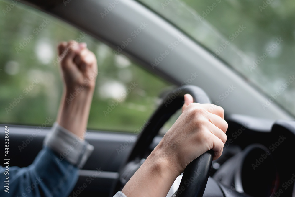 Angry driver shakes her fist in the traffic jam.