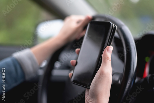 Mobile phone navigation app concept. Mobile phone with blank screen with copy space in the female hands of woman who drives the car.