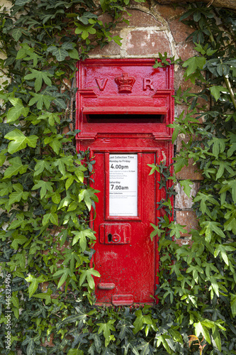 An ivy clad pre 1901 Victorian post box (VR Victoria Regina) in the Exmoor village of Bury, Somerset UK photo