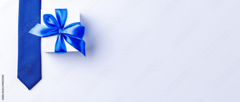 Gift dad. Blue bowtie or tie, white box with bow ribbon on light background. Happy loving family and Fathers Day concept. Gift dad. Blue bowtie or tie, white box with bow ribbon on light background. Happy loving family and Fathers Day concept.