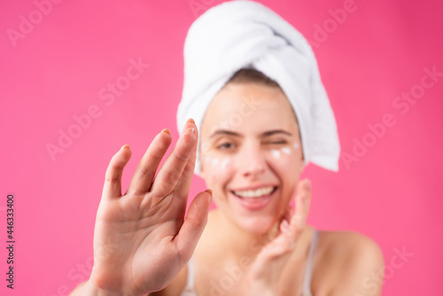 Woman with a facial mask. Charming pretty model after bath wrapped in towel applying using face mask, sensual face. Beautiful woman applying moisturizer on skin using cream touching face.