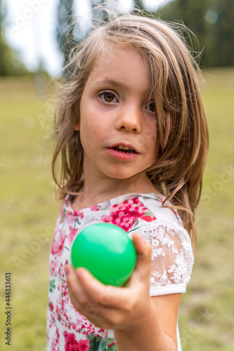 portrait of smiling cute little girl playing with an old tennis racket in a public park