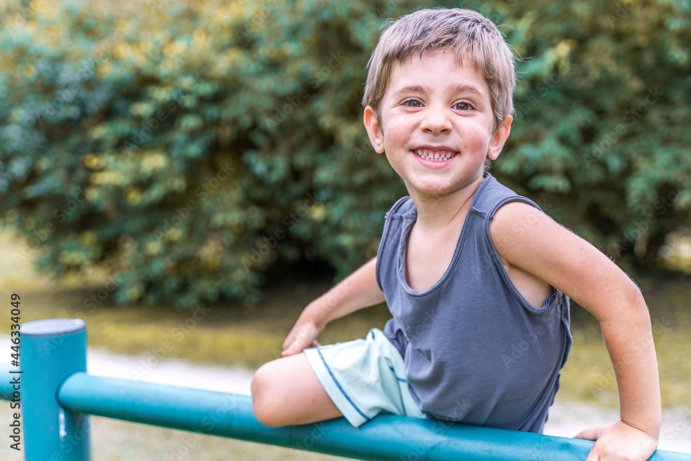 smiling cute child climbing on a metal railing in a public park smiling cute child climbing on a metal railing in a public park