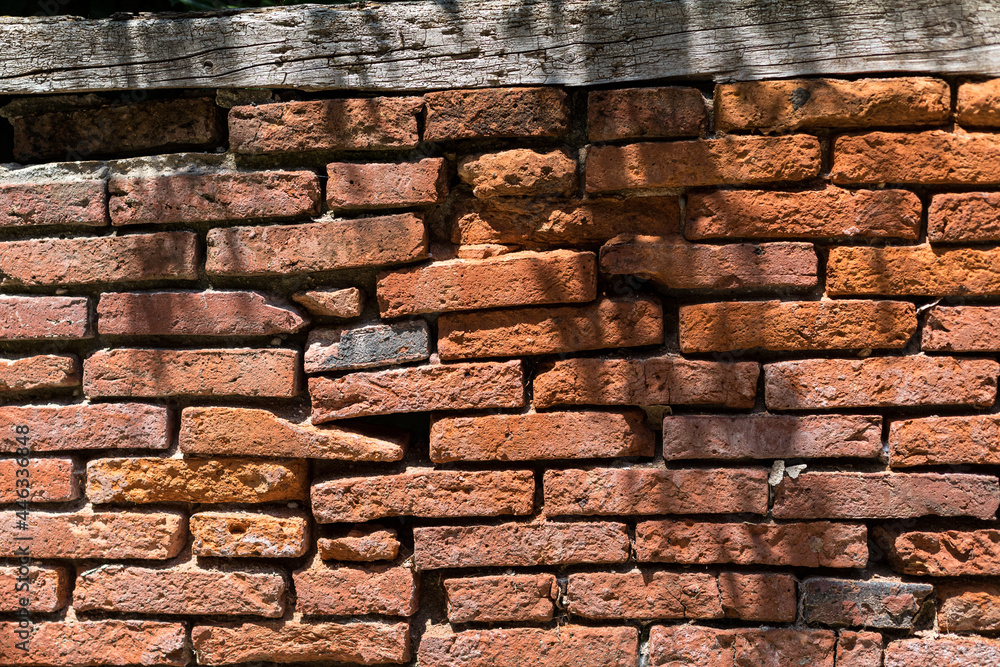 Naklejka premium Old brick wall with a wooden beam at the top.