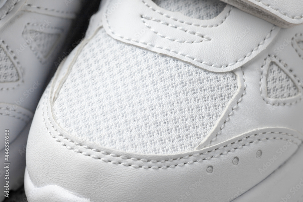 White sneakers close-up on top. Macro photo of children's leather sports sneakers made of fabric with a Velcro fastener. White sneakers close-up on top. Macro photo of children's leather sports sneakers made of fabric with a Velcro fastener.