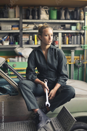 Female mechanician sitting on the car in the garage photo