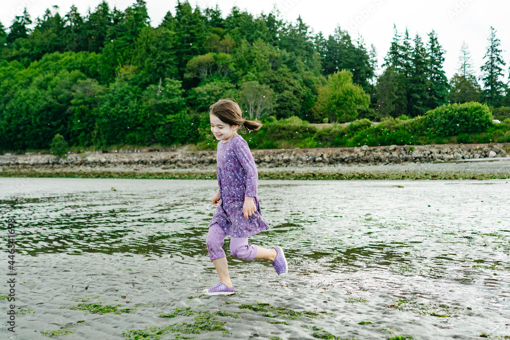 Closeup view of a young child running across a sandy beach