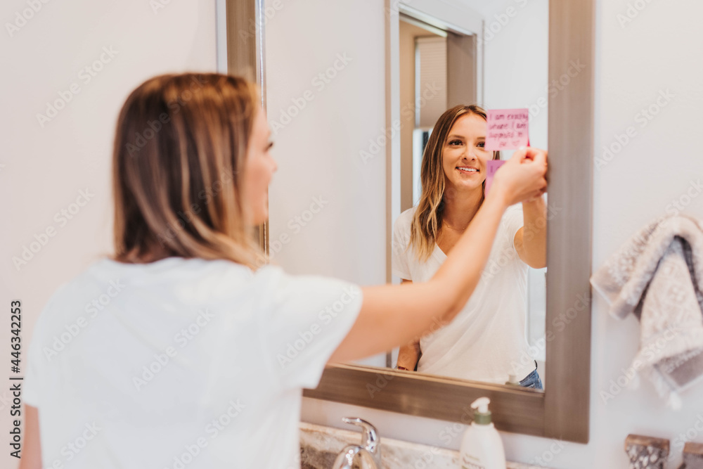 Woman reads affirmations taped to bathroom mirror Woman reads affirmations taped to bathroom mirror
