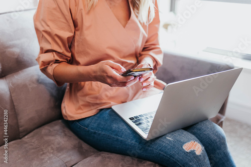 Close up of woman texting on cell phone with a computer on her lap