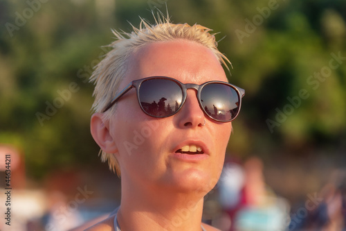 a woman with short blonde hair and sunglasses on beach