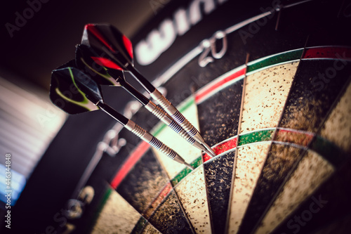 metal-tipped darts stuck in a competition cork dartboard photo