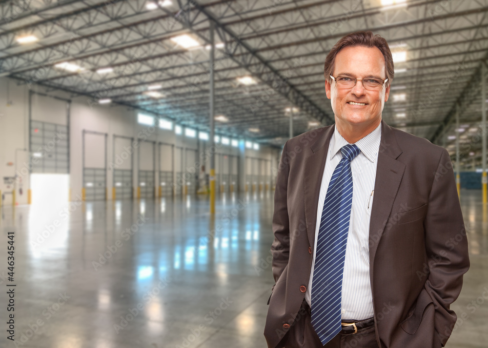 Businessman Wearing Suit and Tie Standing in Empty Industrial Warehouse. Businessman Wearing Suit and Tie Standing in Empty Industrial Warehouse.