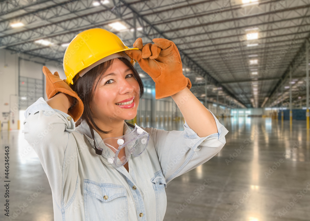 Hispanic Female Contractor Wearing Hard Hat Standing in Empty Industrial Warehouse. Hispanic Female Contractor Wearing Hard Hat Standing in Empty Industrial Warehouse.