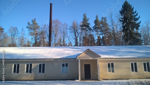 Light one-storey house in winter under the snow and boiler chimney
