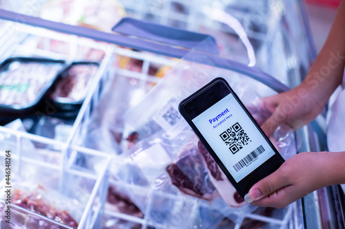 Selective focus to QR code tag on smartphone with blurry frozen food at supermarket, Customer scanning QR Code for information product and payment online.
