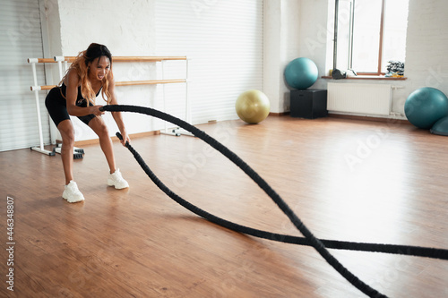 A woman does a body stretching workout in a bright fitness studio. Athletic physique, cardio training for burning calories. A healthy lifestyle at a young age. © muse studio