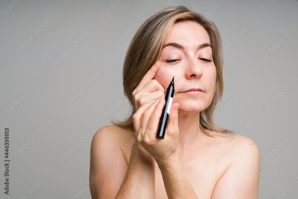 Beautiful mature woman applying eye makeup Beautiful mature woman applying eye makeup