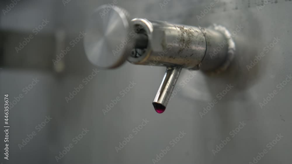 red wine production, closeup view of faucet of steel barrel with drop red wine production, closeup view of faucet of steel barrel with drop