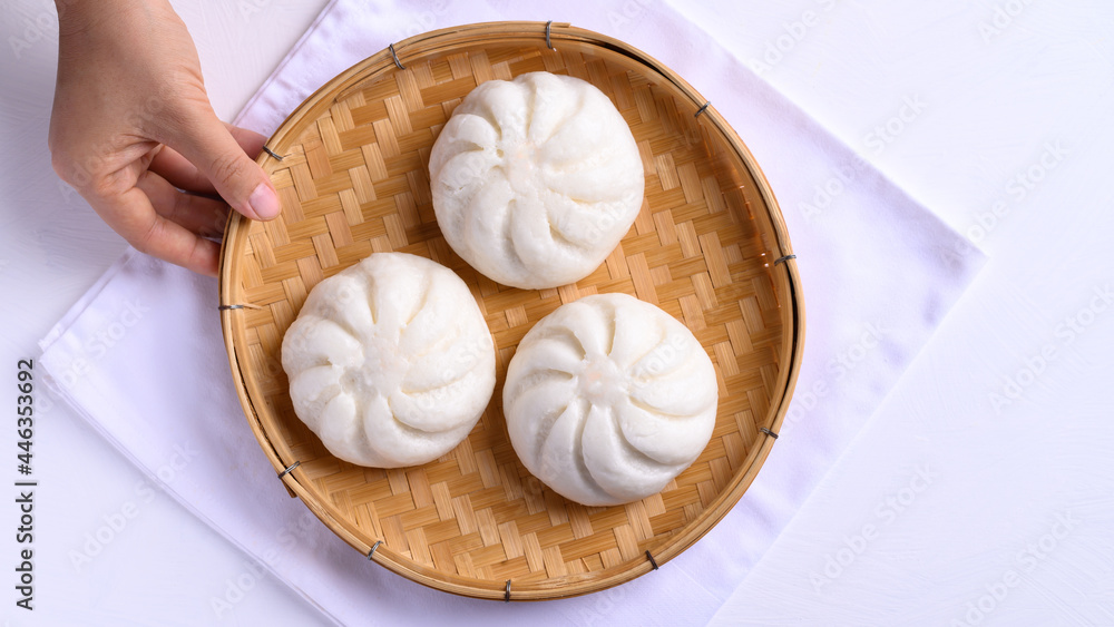 Steamed bun stuffed with minced pork on bamboo basket with hand, Asian food Steamed bun stuffed with minced pork on bamboo basket with hand, Asian food