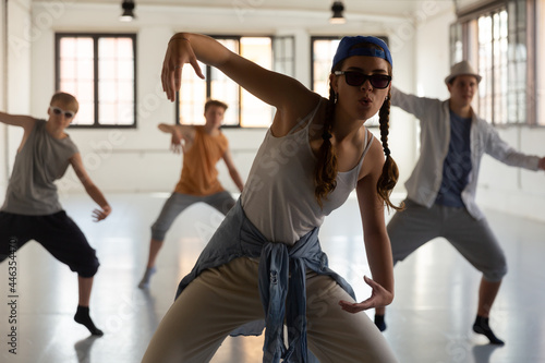 Teenage girl performing hip hop elements at group dance training in studio