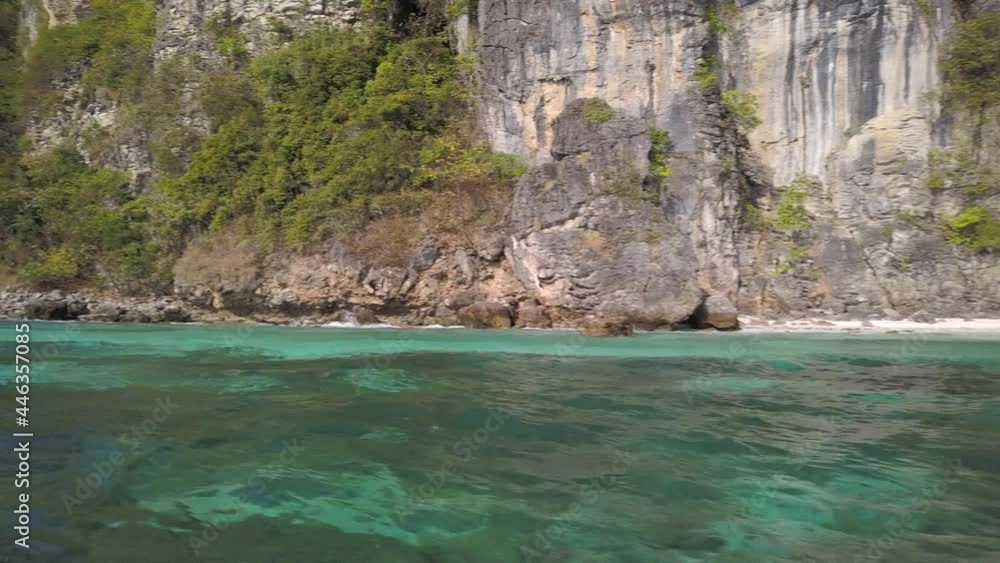 Panning dolly shot of limestone karst tropical island, blue sky, white sand beach. Traveling through turquoise green ocean water of the Andaman sea near Phuket. Mosquito island Koh Yung, Thailand. Panning dolly shot of limestone karst tropical island, blue sky, white sand beach. Traveling through turquoise green ocean water of the Andaman sea near Phuket. Mosquito island Koh Yung, Thailand.