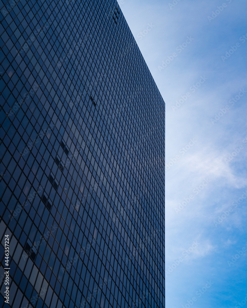 large building full of windows with clouds and blue sky in background large building full of windows with clouds and blue sky in background