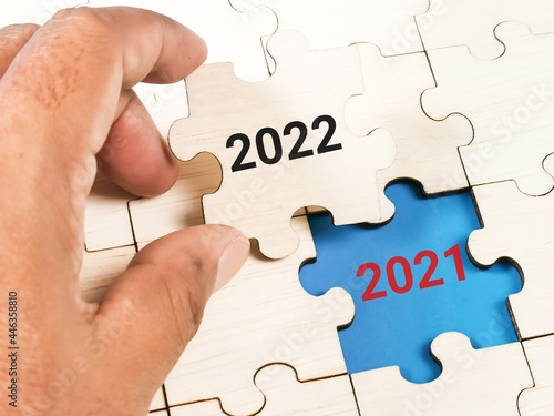 New year concept. Hand replacing puzzle pieces with 2021 to 2022.